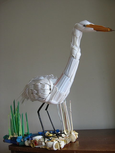 a bird made out of plastic sitting on top of a table next to sea shells