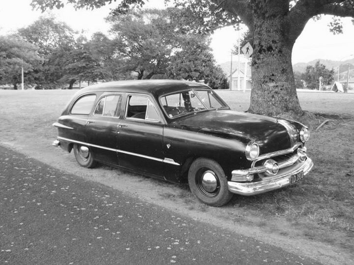 an old black car parked next to a tree