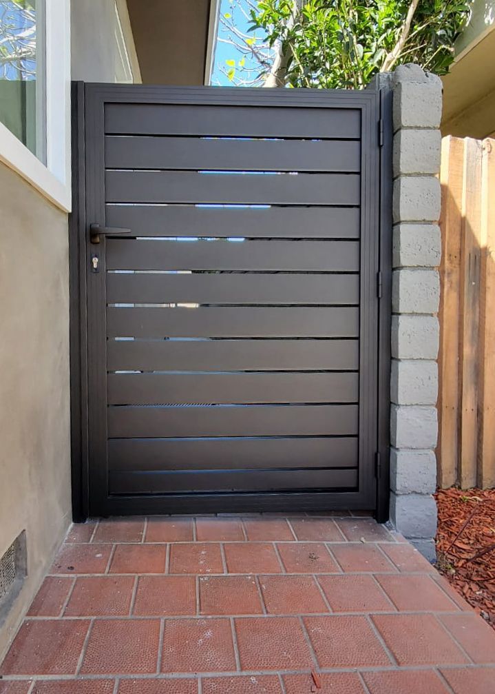 a gate that is on the side of a house with brick flooring and red bricks