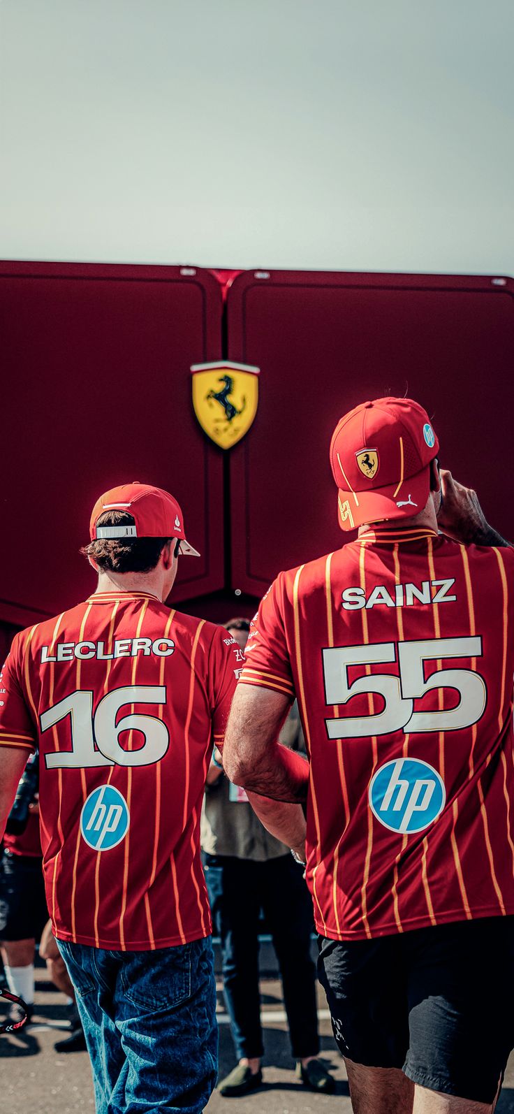 two men in red shirts are walking down the street with their backs to each other