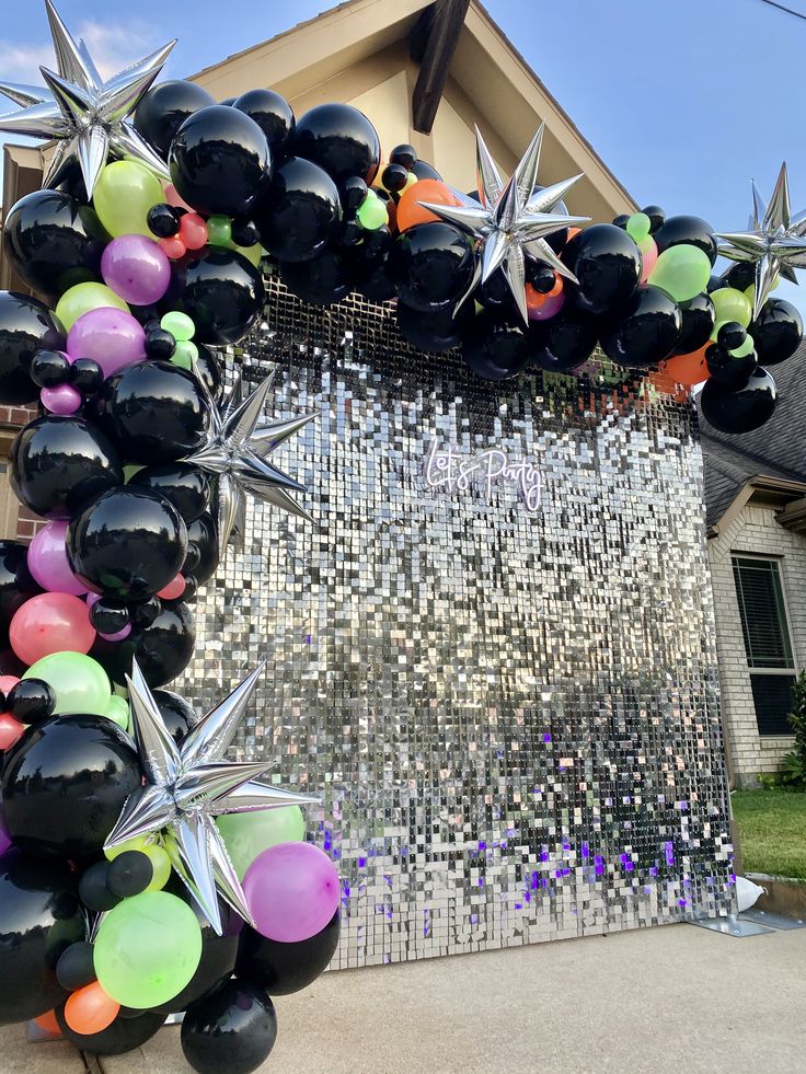 a balloon arch with stars and balloons attached to the front of a home in an area that has been decorated for christmas