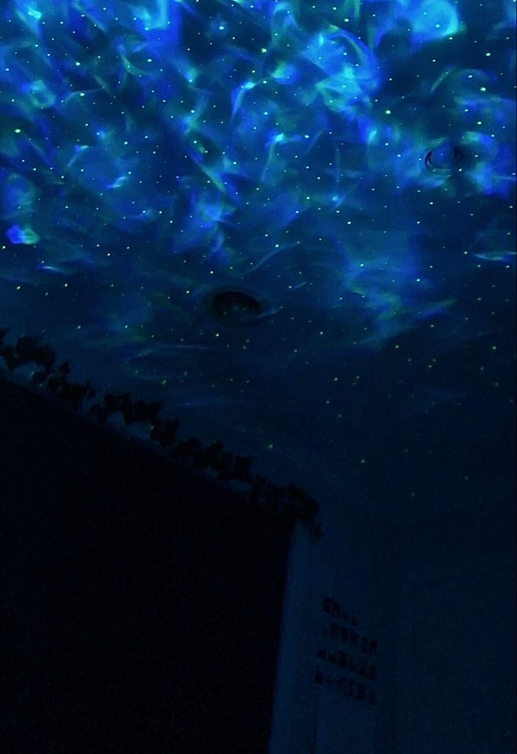 the ceiling is lit up with blue lights and stars in the night sky above it