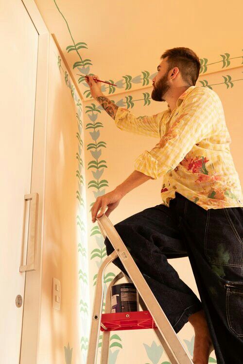 a man on a ladder painting the wall