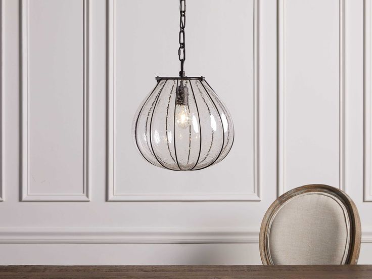 a light fixture hanging from the ceiling over a wooden table with a chair in front of it