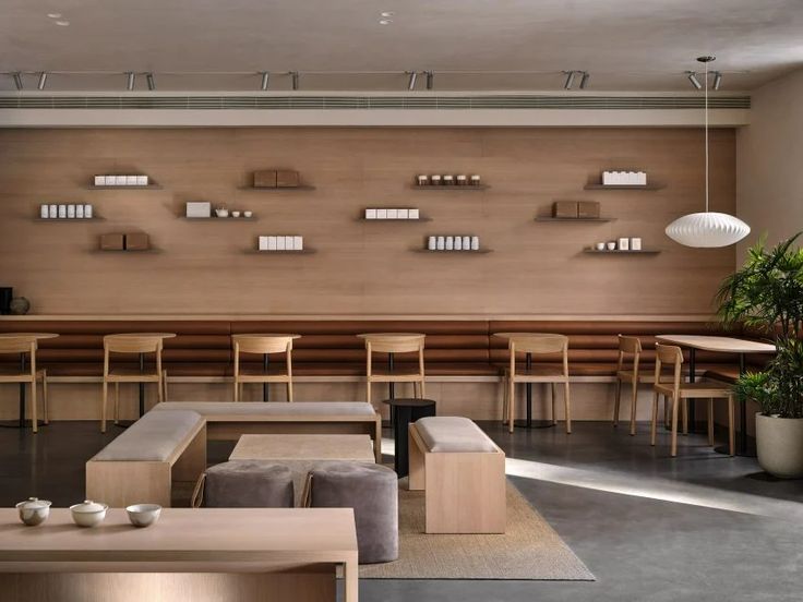 an empty restaurant with wooden tables and chairs in front of a wall filled with shelves