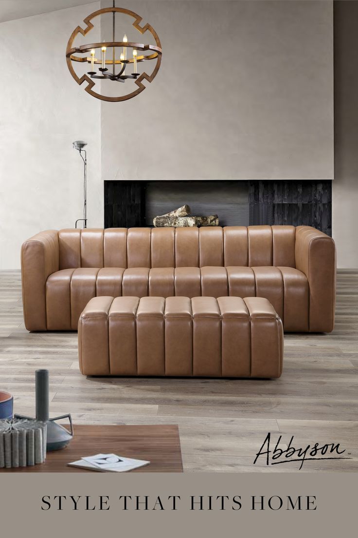 a brown leather couch sitting in front of a fire place under a chandelier