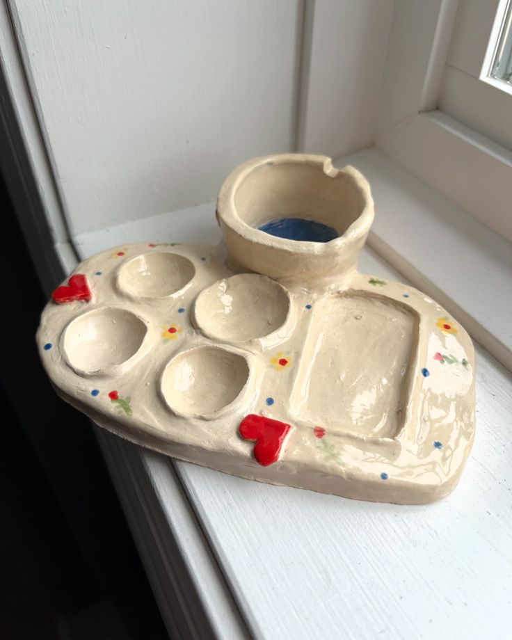 a ceramic tray with two bowls on top of it next to a window sill