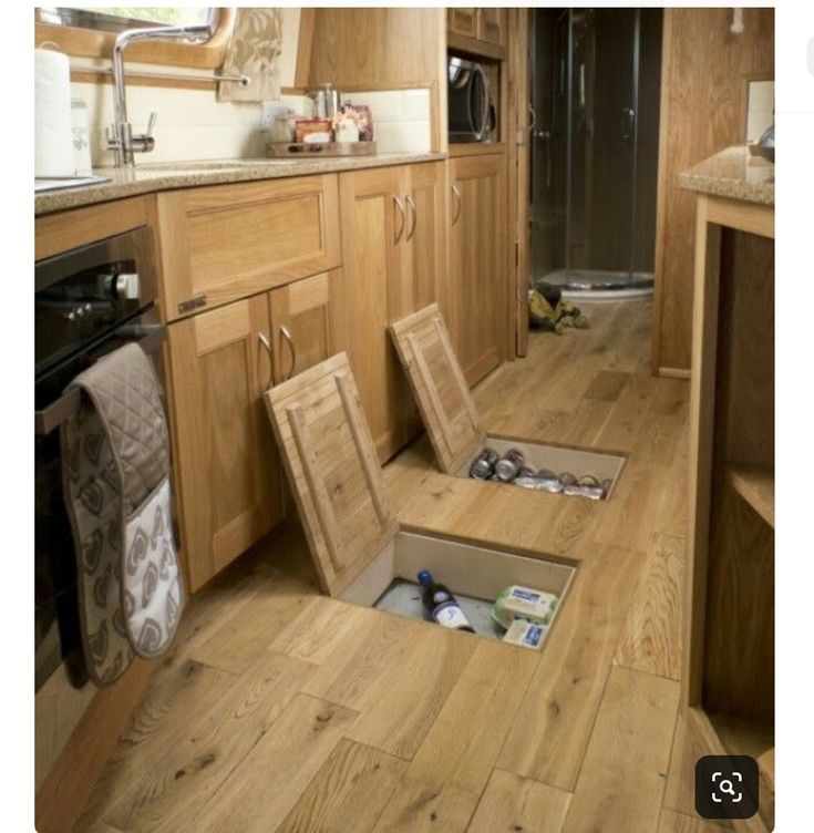 an open floor drain in the middle of a kitchen with wooden cabinets and drawers on both sides