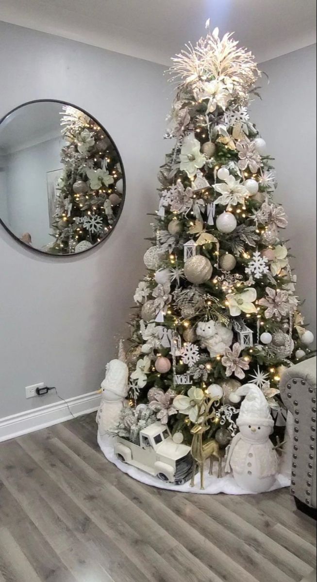 a decorated christmas tree in the corner of a room with a mirror on the wall