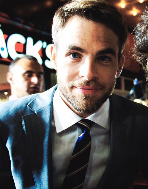 a man wearing a suit and tie standing next to another man in front of a bar