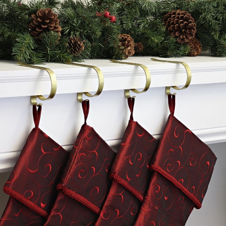 three christmas stockings hanging from hooks on a mantle