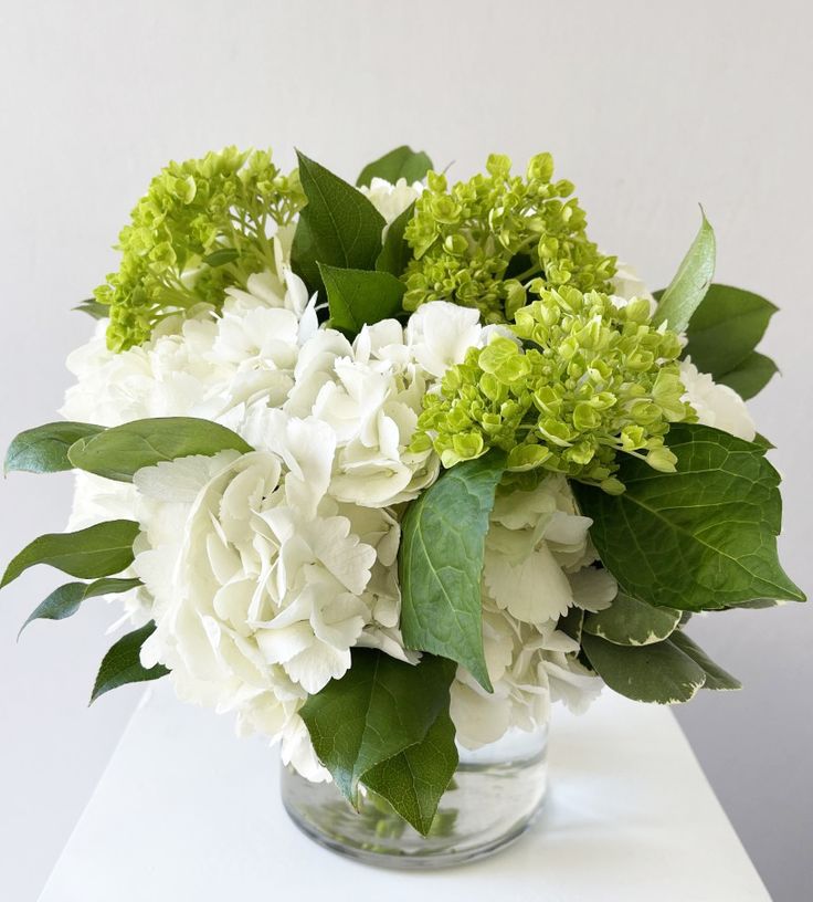 a glass vase filled with white and green flowers