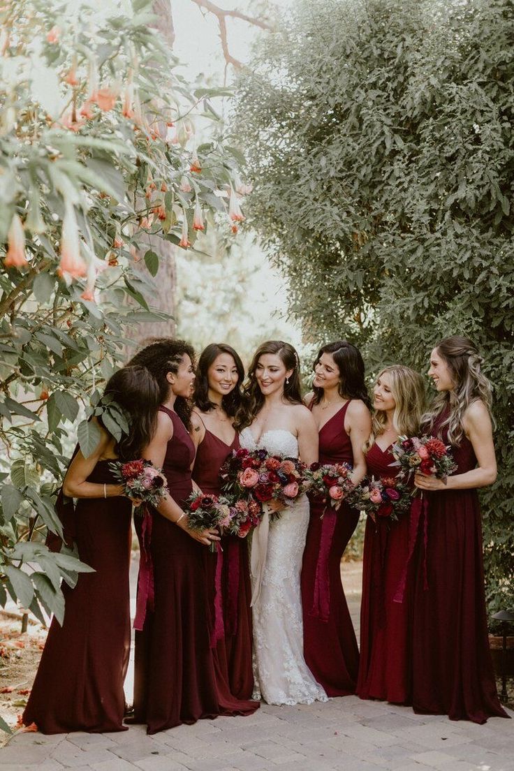 a group of women standing next to each other holding bouquets in their hands and smiling