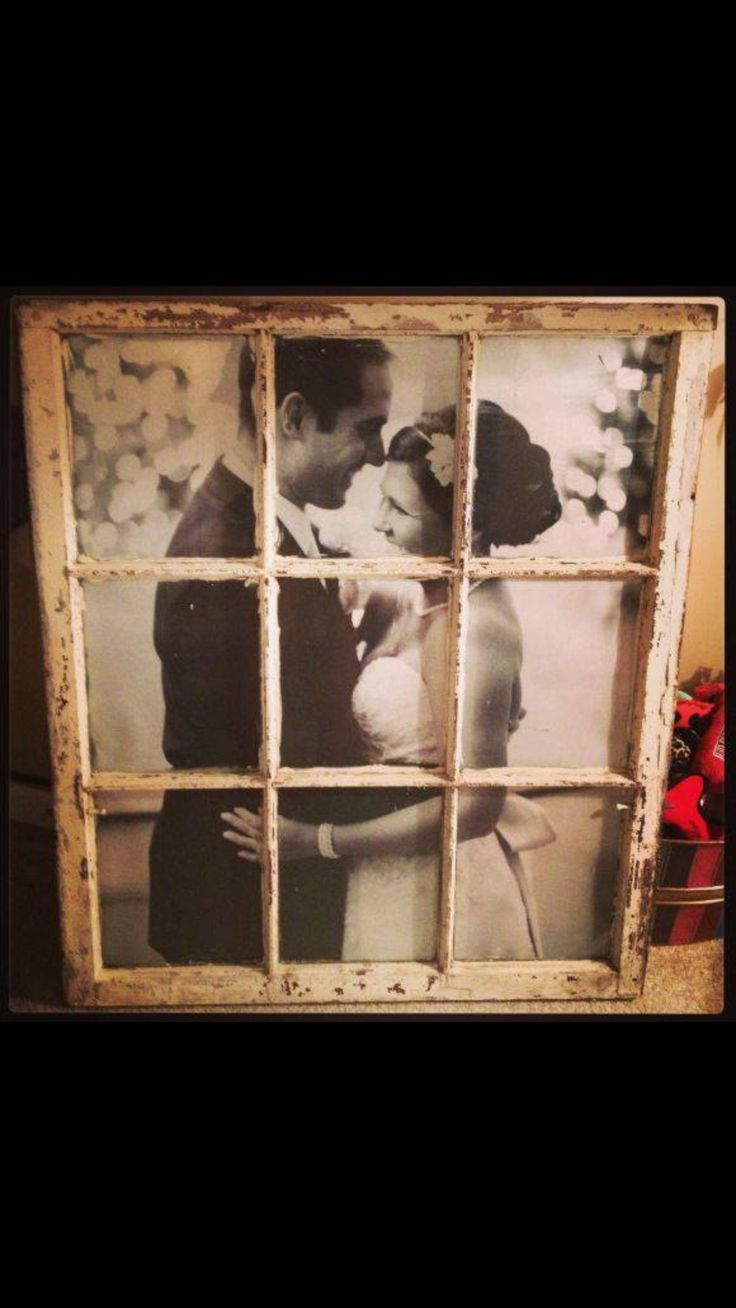 an old window with photos of a couple kissing in front of it and the windows are dirty