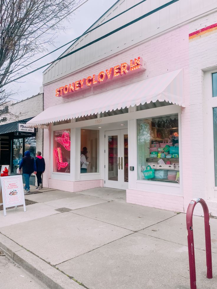 a store front with people walking in the doorway and on the sidewalk near it is a sign that says store of overex