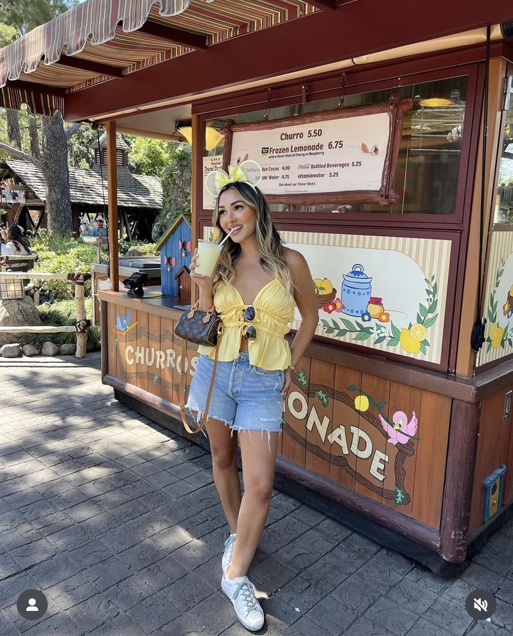 a woman standing in front of a food stand with her hands on her hips and smiling at the camera