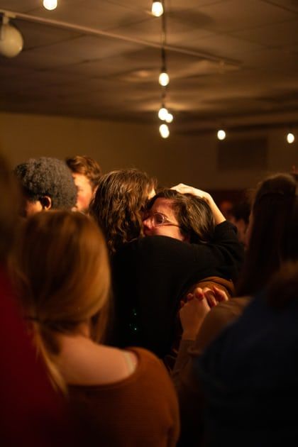 a group of people standing in a room with their arms around each other and covering their eyes