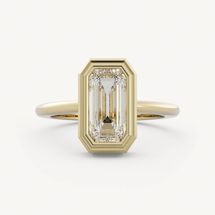 a yellow gold ring with an emerald cut diamond