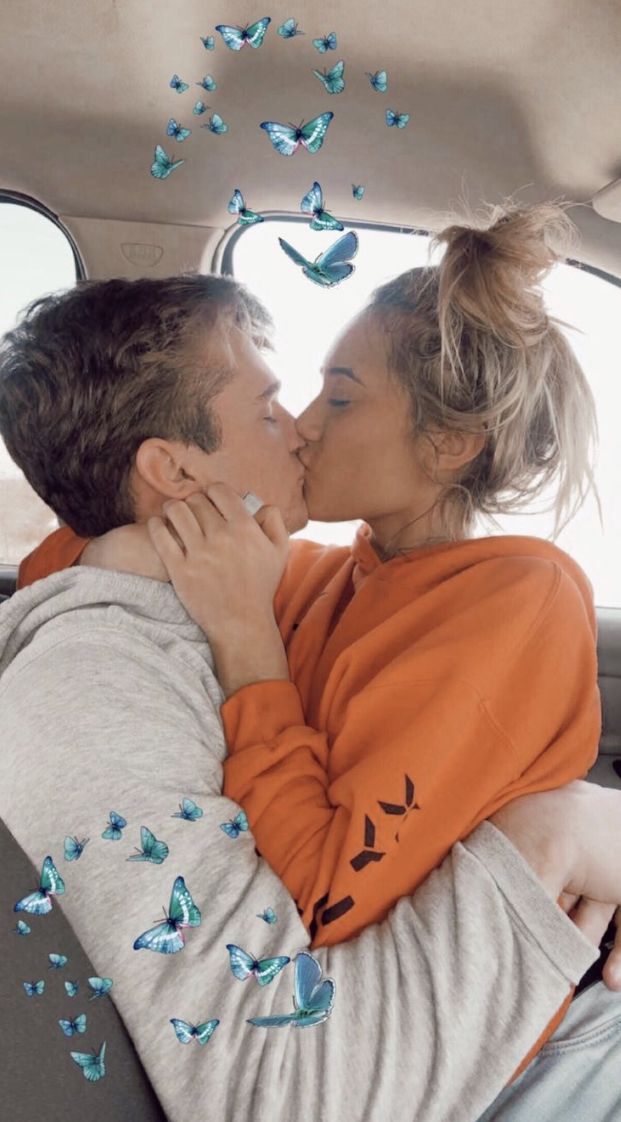 a man and woman kissing in the back seat of a car with butterflies flying around them