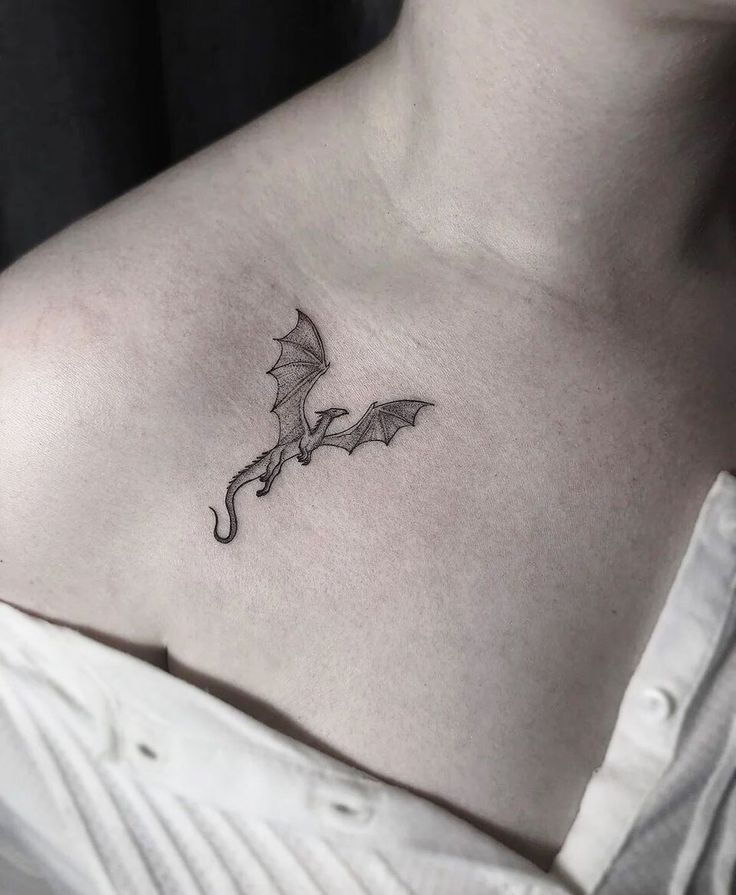 a woman's chest with a small dragon tattoo on it