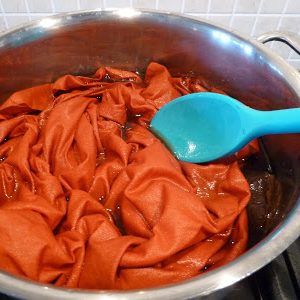 a blue spoon sitting in a pot full of red cloths on top of a stove