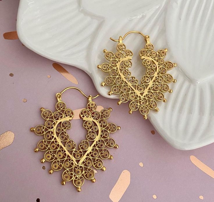 These filigree earrings are crafted from sterling silver with a lavish 24k gold plating, exuding opulence. Featuring a heart design interwoven with floral accents, each pair is a statement of elegance and a homage to the art of filigree. Ideal for enhancing any ensemble, they speak of a love for beauty and meticulous attention to every link and curve. Perfect for the chic individual seeking an accessory with history and artistry. Thanks Gold Earrings For Valentine's Day Celebration, Festive Filigree Hoop Earrings Gift, Traditional Gift Heart Earrings Pierced, Gold Filigree Hoop Earrings For Festivals, Ornate Gold Hoop Earrings For Gift, Elegant Gold Heart Earrings In Brass, Gold Handmade Hoop Earrings For Valentine's Day, Ornate Gold Jewelry For Valentine's Day, Gold Hoop Earrings With Intricate Design For Gift