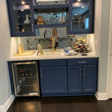 a small kitchen with blue cabinets and white counter tops, along with dark wood flooring