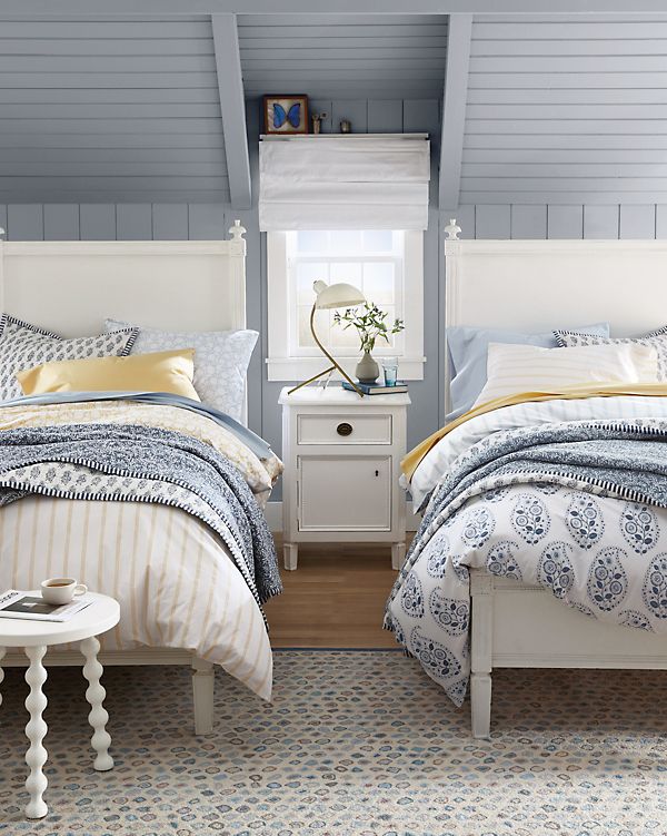 two beds with blue and yellow comforters in a bedroom next to each other on a rug