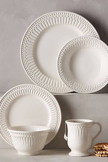 a white dinner plate with two cups and saucers next to it on a table