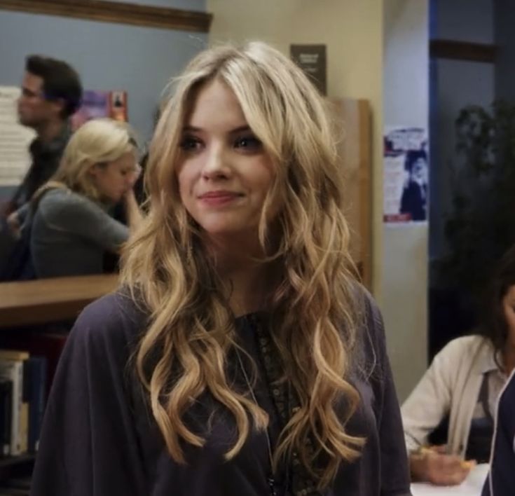 a woman with long hair standing in front of two other women sitting at a table