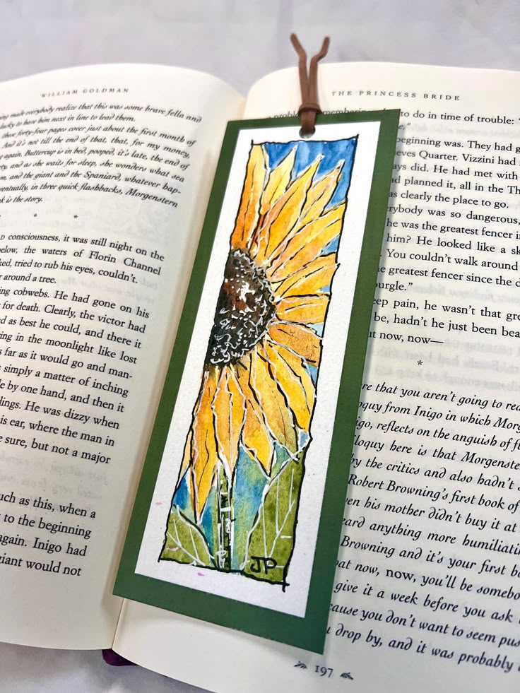 an open book with a sunflower painted on the front and back cover in watercolor