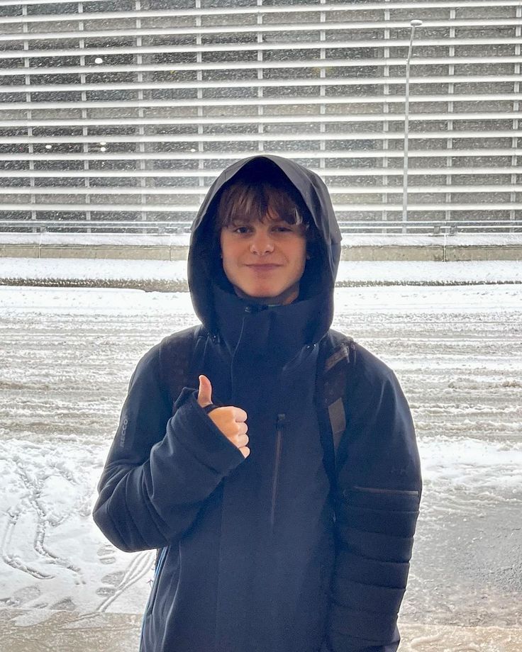 a person standing in the snow giving a thumbs up