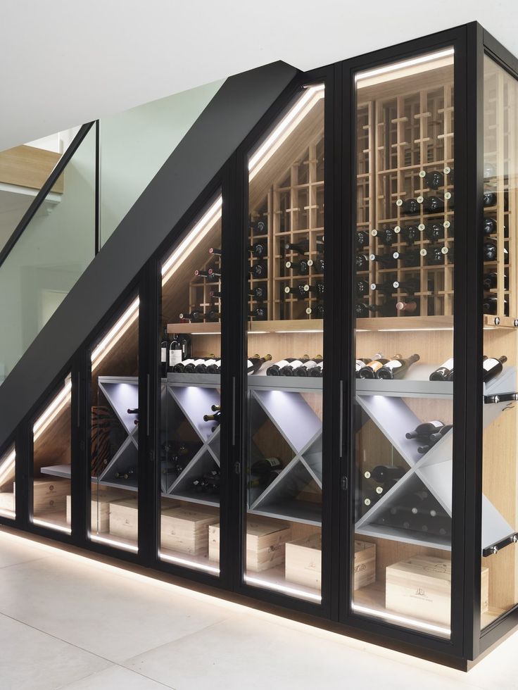 a wine cellar with many bottles in it and stairs leading up to the second floor