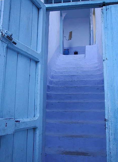 an open door leading to a blue staircase