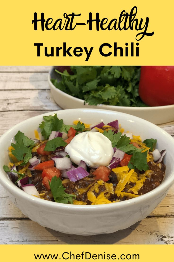 hearty turkey chili with sour cream and cilantro in a white bowl on a wooden table