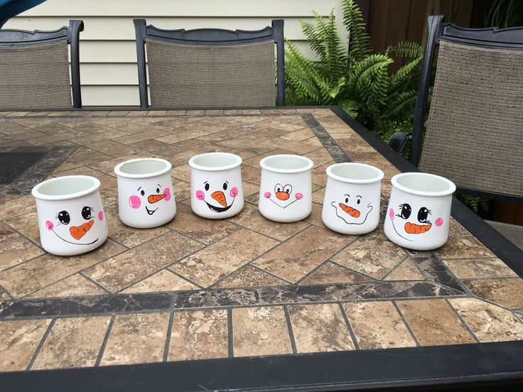 five frosty mugs sitting on top of a table with faces painted on them