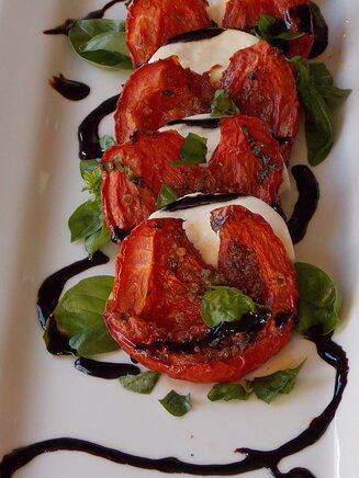 a white plate topped with sliced tomatoes covered in sauce