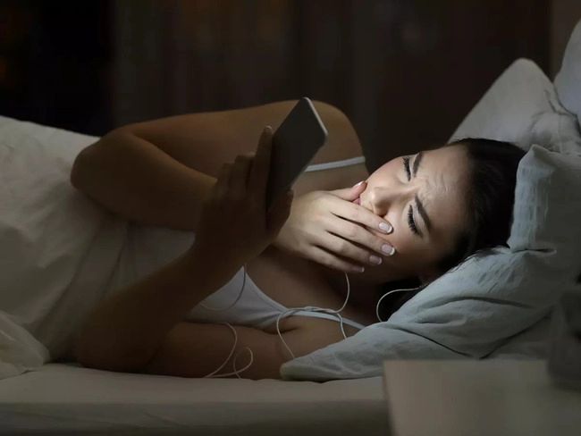 a woman laying in bed with her head on the pillow and reading a book at night