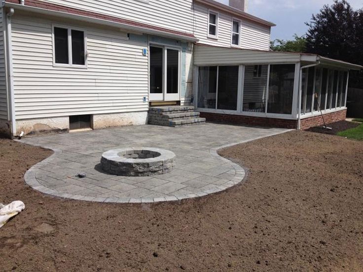 an outdoor fire pit in the middle of a graveled area next to a house