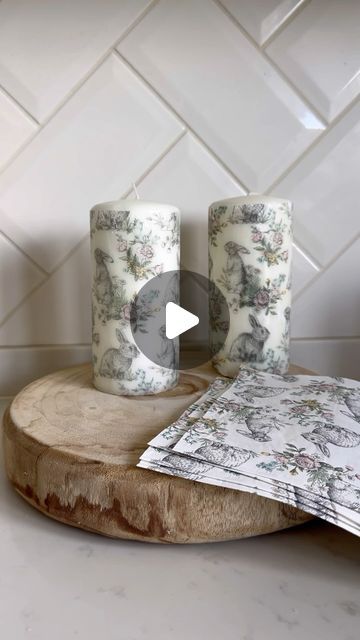 two white candles sitting on top of a wooden table next to a piece of paper