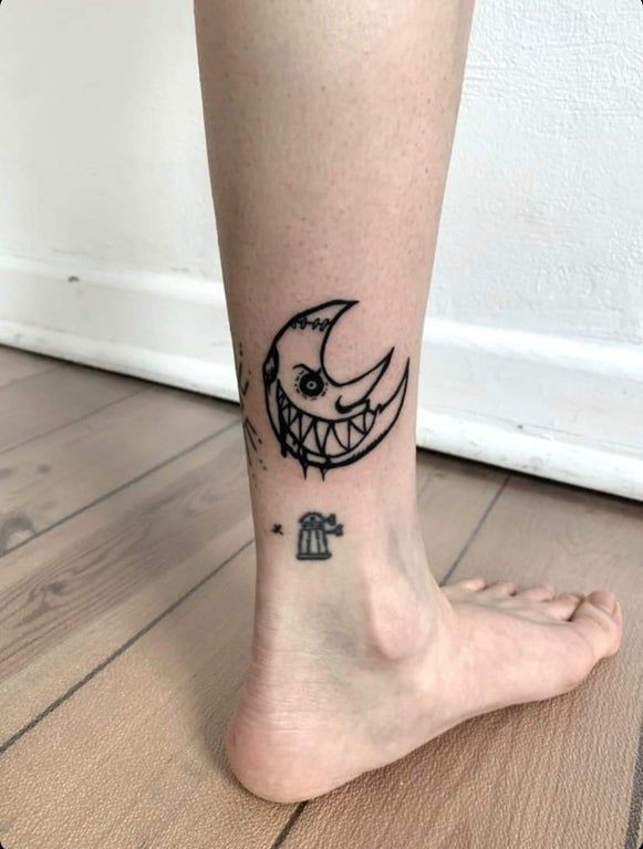 a person with a small tattoo on their leg and the foot is shown in black ink