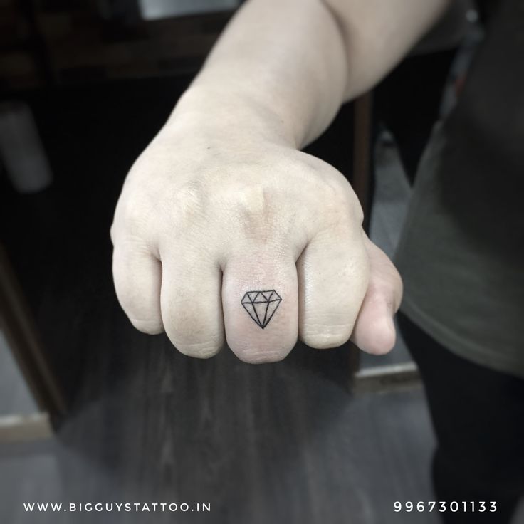 a hand with a small diamond tattoo on it