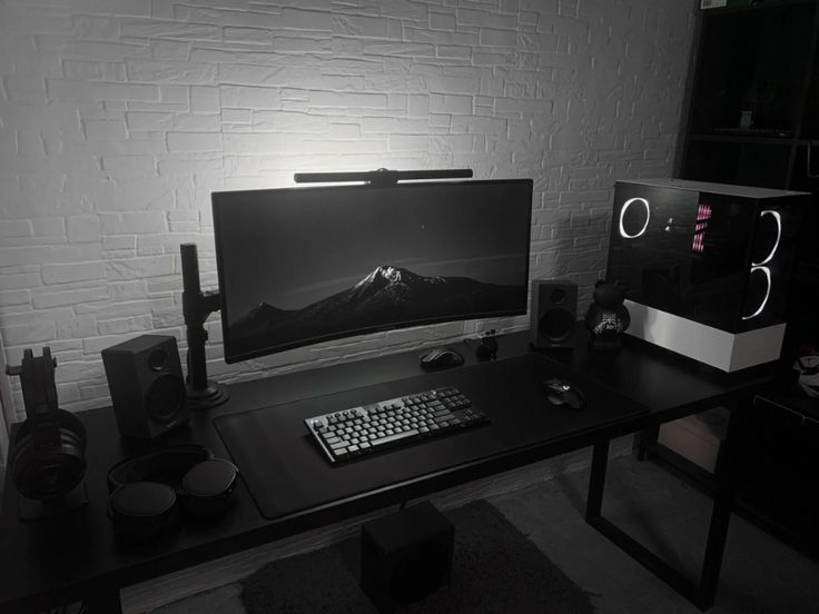 a desk with a keyboard, mouse and monitor on it in front of a brick wall