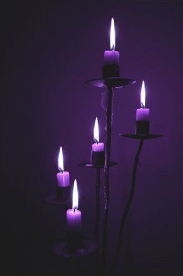 five lit candles in a dark room with purple lighting