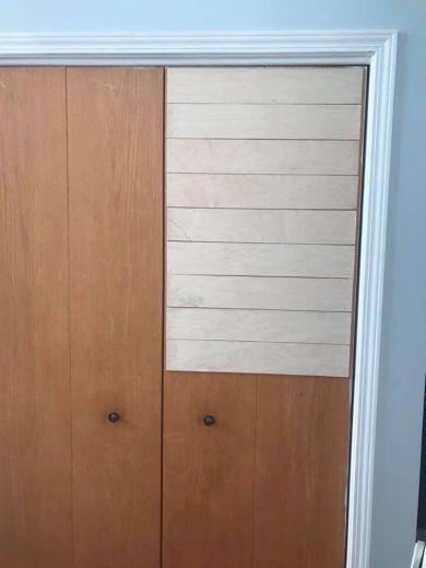 two wooden doors in a room with white trim on the door and wood paneling