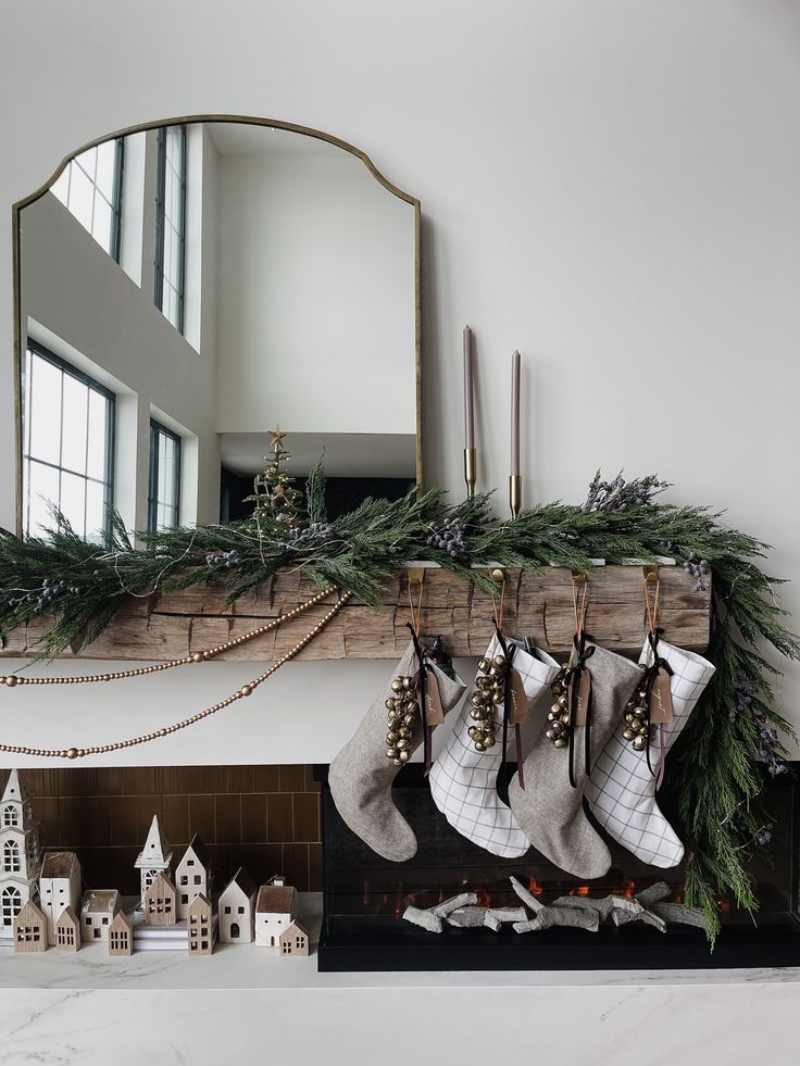 stockings hanging from a mantel over a fireplace with christmas decorations and candles on it