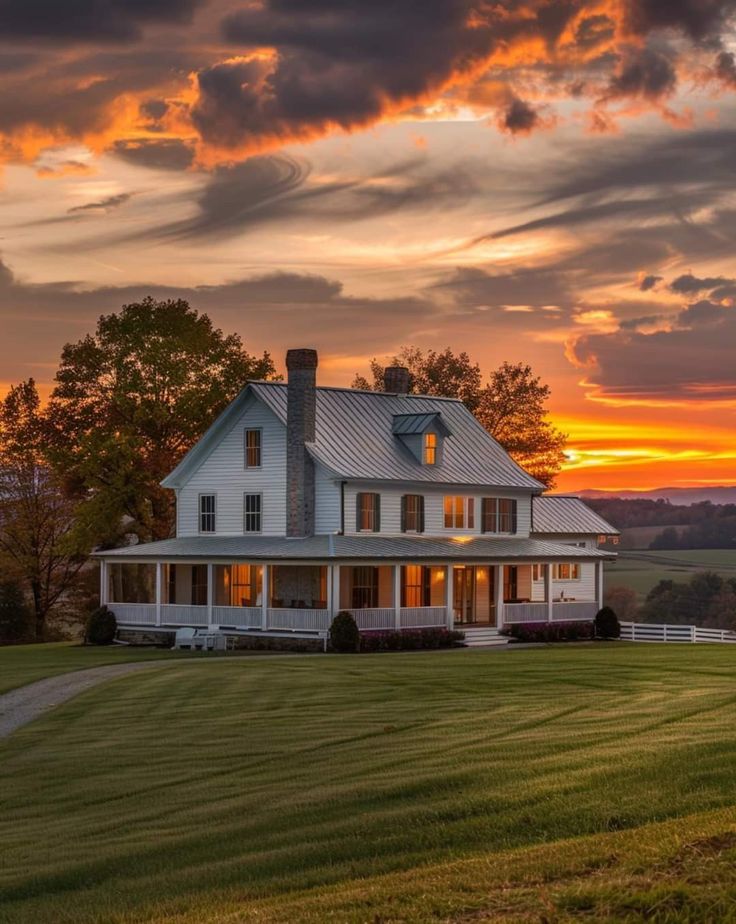 a large white house sitting on top of a lush green field under a cloudy sky