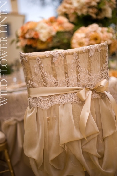 the back of a chair with lace on it and bows at the waist, along with flowers in the background