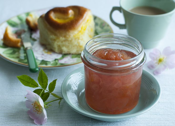 a jar of jam sitting on top of a plate next to a cup