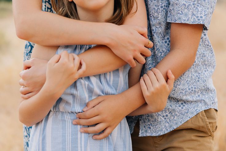 two children hugging each other in the middle of a field